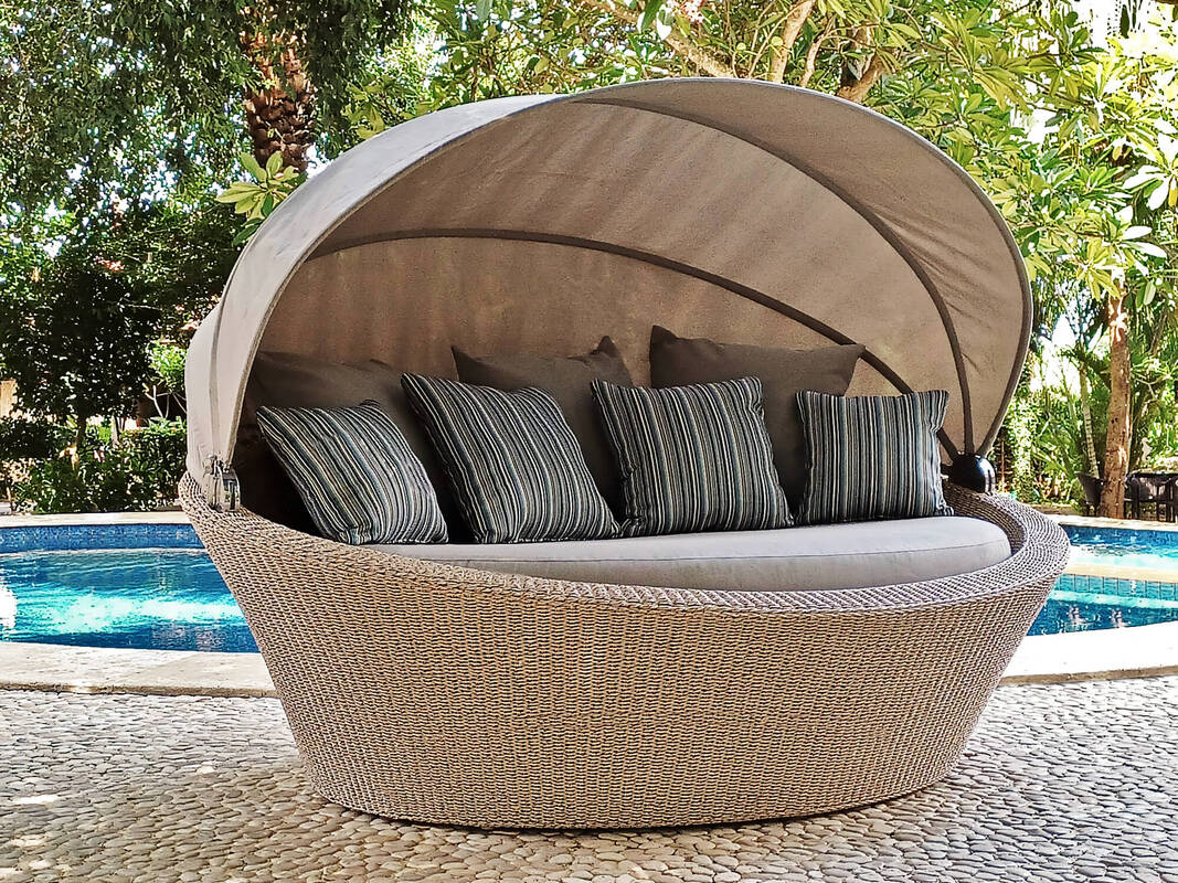 Daybed de fibra trenzada para exterior con capota y cojines decorativos en una piscina en una villa en Estepona, Málaga, Costa del sol
