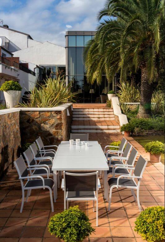 Imagen de mesa extensible para terraza con diez sillones en aluminio blanco